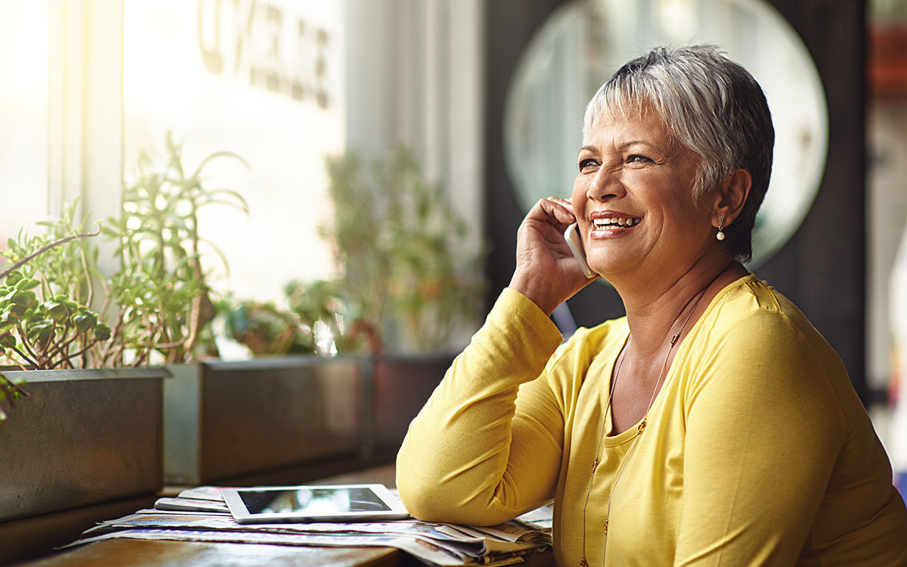 Kvinna i gul tröja pratar i en mobil