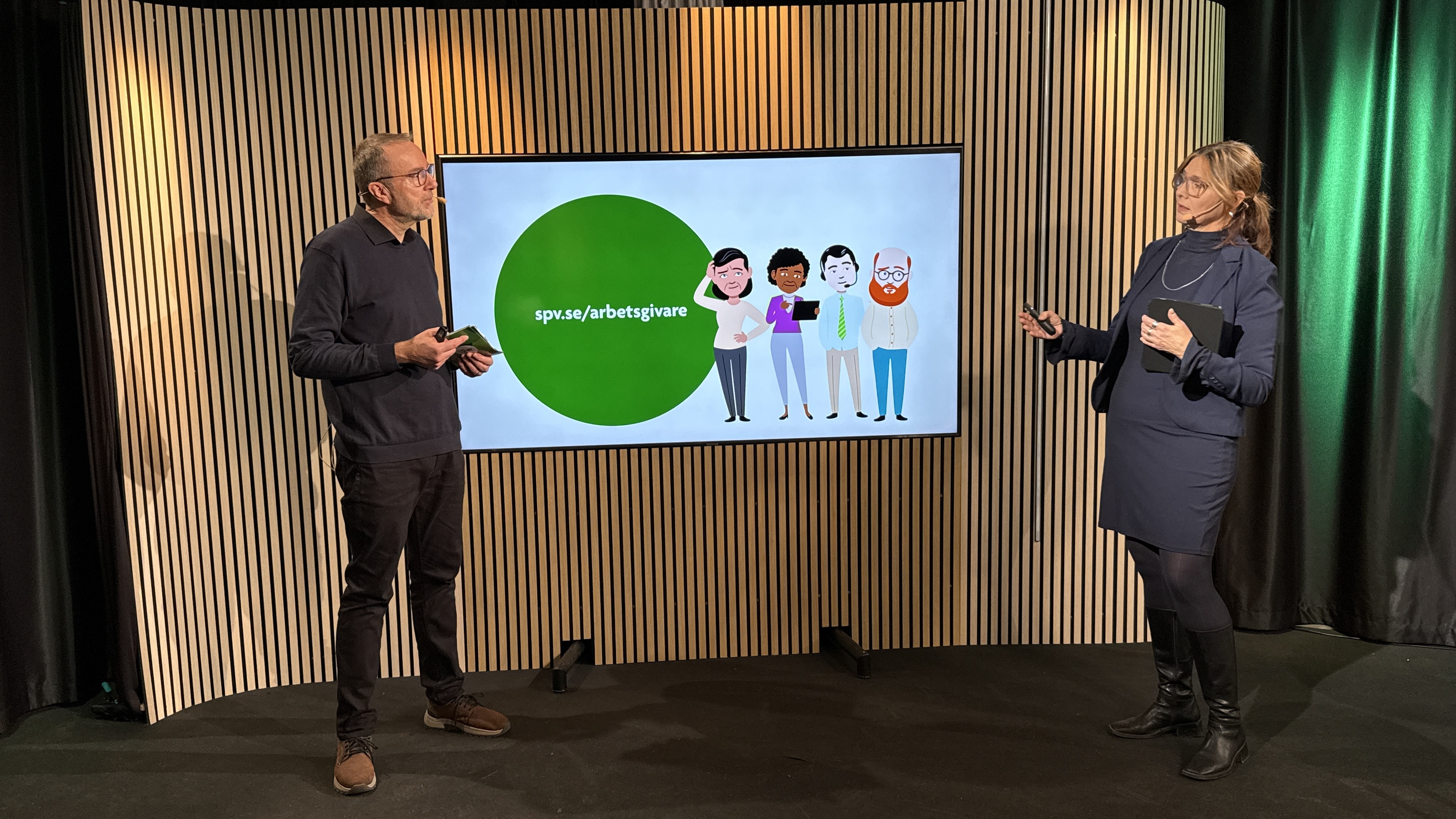 En man och en kvinna st&aring;r och f&ouml;rel&auml;ser vid en stor bildsk&auml;rm