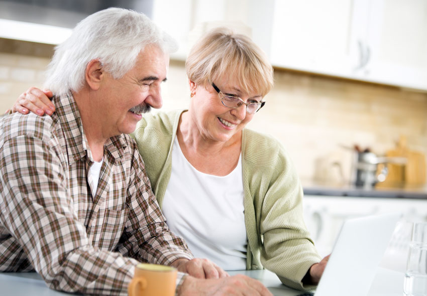 Par som sitter vid sin dator i ett kök